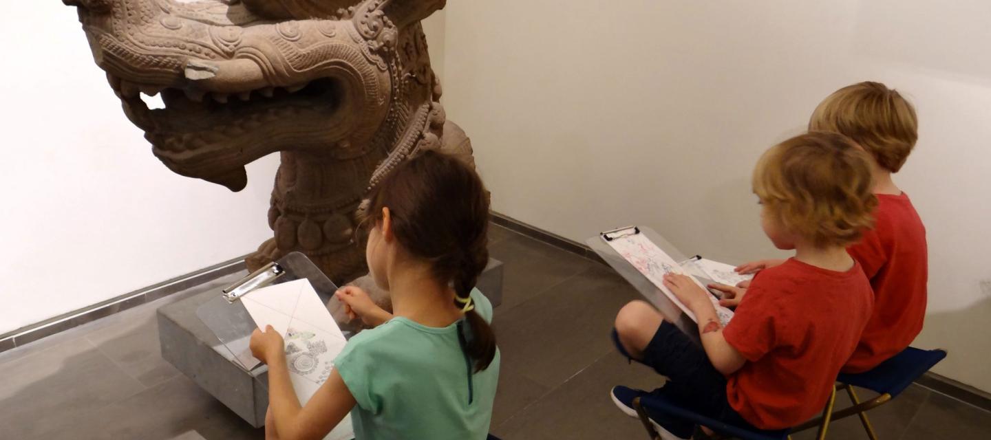 Image de trois enfants dessinant les œuvres du musée